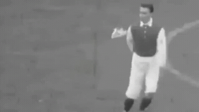 A Black And White Photo Of A Man Running With A Soccer Ball On A Field . GIF