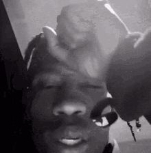 A Black And White Photo Of A Man 'S Face With A Hand On His Forehead . GIF