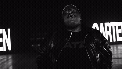 A Black And White Photo Of A Man Singing In Front Of A Sign That Says " Garten " GIF