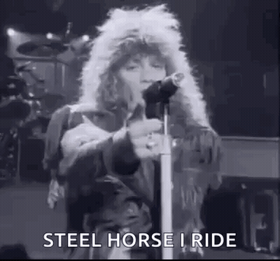 A Black And White Photo Of A Man Singing Into A Microphone On Stage . GIF