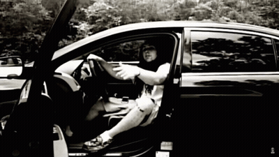 A Black And White Photo Of A Man Sitting In A Car With The Door Open GIF