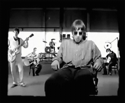 A Black And White Photo Of A Man Sitting In A Chair In Front Of A Band GIF