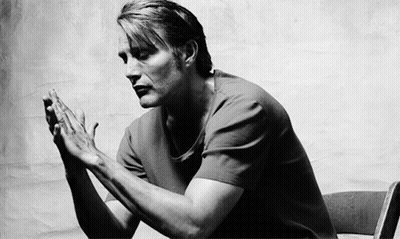 A Black And White Photo Of A Man Sitting In A Chair With His Hands Folded In Prayer . GIF