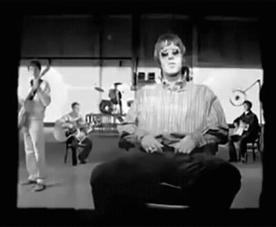 A Black And White Photo Of A Man Sitting In Front Of A Band GIF