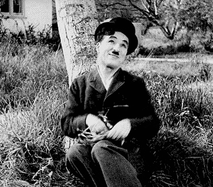 A Black And White Photo Of A Man Sitting Next To A Tree . GIF