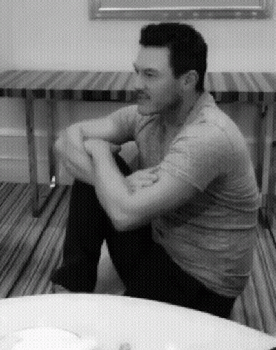 A Black And White Photo Of A Man Sitting On The Floor GIF