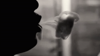 A Black And White Photo Of A Man Smoking A Cigarette . GIF