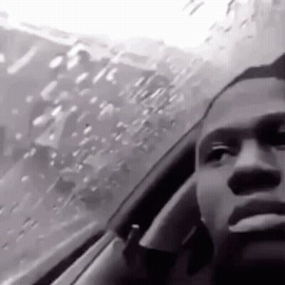 A Black And White Photo Of A Man Smoking A Cigarette While Sitting In A Car . GIF