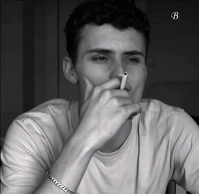A Black And White Photo Of A Man Smoking A Cigarette With The Letter B On The Bottom Right GIF