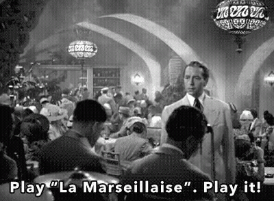 A Black And White Photo Of A Man Standing In A Crowded Restaurant . GIF