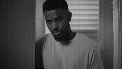A Black And White Photo Of A Man Standing In A Doorway . GIF