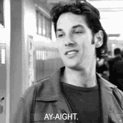A Black And White Photo Of A Man Standing In A Hallway Talking To Someone . GIF