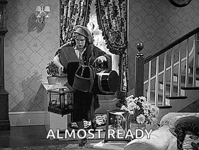 A Black And White Photo Of A Man Standing In A Living Room Holding A Bag . GIF