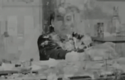 A Black And White Photo Of A Man Standing In A Room Covered In Paint . GIF