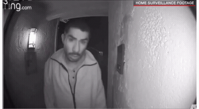 A Black And White Photo Of A Man Standing In Front Of A Door With The Words Home Surveillance Footage On The Bottom GIF