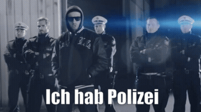A Black And White Photo Of A Man Standing In Front Of A Group Of Police Officers With Ich Hab Polizei Written On The Bot GIF