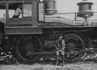 A Black And White Photo Of A Man Standing In Front Of A Train . GIF