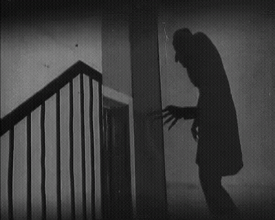 A Black And White Photo Of A Man Standing Next To A Staircase GIF
