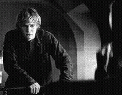 A Black And White Photo Of A Man Standing Next To A Wall Holding A Knife . GIF