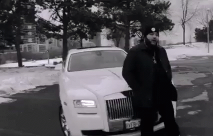 A Black And White Photo Of A Man Standing Next To A White Limousine In A Parking Lot . GIF