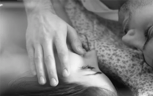A Black And White Photo Of A Man Touching A Woman 'S Face While Laying On A Bed . GIF