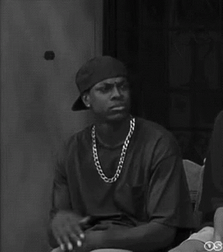 A Black And White Photo Of A Man Wearing A Baseball Cap And A Chain . GIF