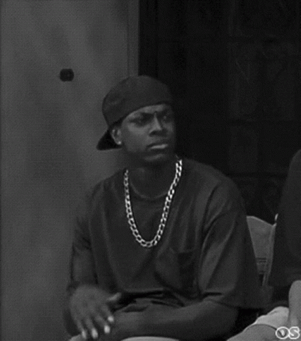A Black And White Photo Of A Man Wearing A Baseball Cap And Chain . GIF