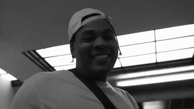 A Black And White Photo Of A Man Wearing A Baseball Cap And Smiling GIF