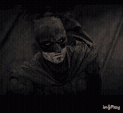 A Black And White Photo Of A Man Wearing A Batman Mask . GIF