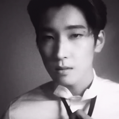 A Black And White Photo Of A Man Wearing A Bow Tie . GIF