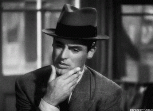 A Black And White Photo Of A Man Wearing A Fedora Hat GIF