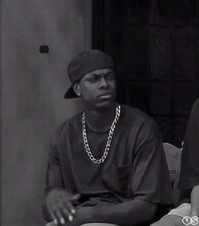 A Black And White Photo Of A Man Wearing A Hat And A Chain Around His Neck . GIF