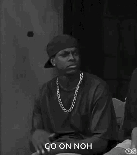 A Black And White Photo Of A Man Wearing A Hat And A Necklace Saying `` Go On Noh '' . GIF