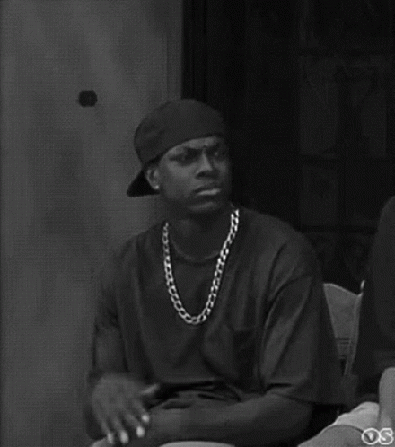 A Black And White Photo Of A Man Wearing A Hat And Necklace . GIF