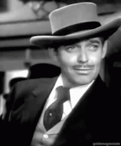 A Black And White Photo Of A Man Wearing A Hat And Tie GIF