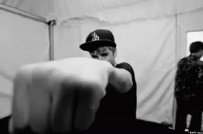 A Black And White Photo Of A Man Wearing A Hat Pointing His Finger At The Camera . GIF