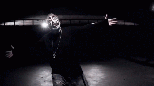 A Black And White Photo Of A Man Wearing A Mask And A Necklace GIF