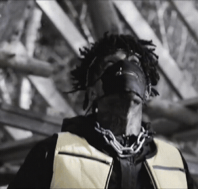 A Black And White Photo Of A Man Wearing A Mask And A Yellow Vest . GIF