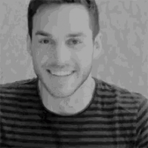 A Black And White Photo Of A Man Wearing A Striped Shirt Smiling . GIF