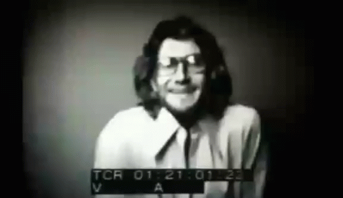 A Black And White Photo Of A Man Wearing Glasses And A White Shirt . GIF