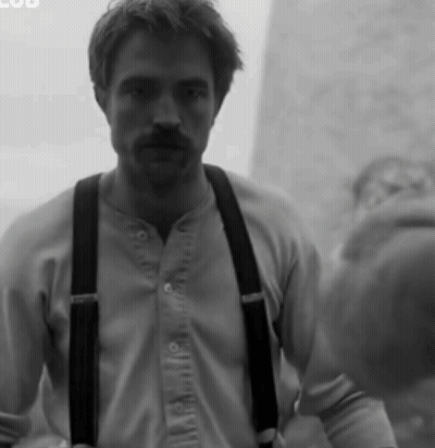 A Black And White Photo Of A Man Wearing Suspenders And A Shirt GIF