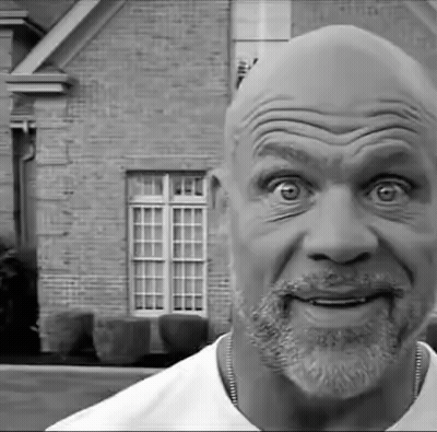 A Black And White Photo Of A Man With A Beard Making A Funny Face In Front Of A Brick House . GIF