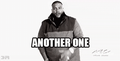 A Black And White Photo Of A Man With A Beard Wearing A Sweater And Standing With His Hands In His Pockets . GIF