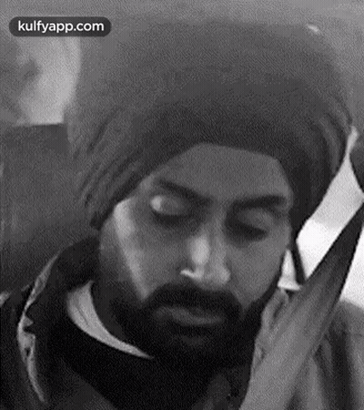 A Black And White Photo Of A Man With A Beard Wearing A Turban And Talking On A Cell Phone . GIF
