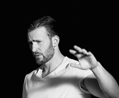 A Black And White Photo Of A Man With A Beard Wearing A White T-Shirt And A Necklace . GIF