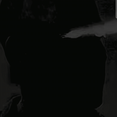 a black and white photo of a man with a brick wall behind him .