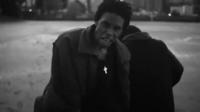 A Black And White Photo Of A Man With A Cross On His Neck . GIF