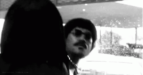 A Black And White Photo Of A Man With A Mustache Wearing Sunglasses . GIF