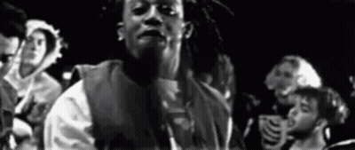 A Black And White Photo Of A Man With Dreadlocks Standing In Front Of A Crowd Of People . GIF
