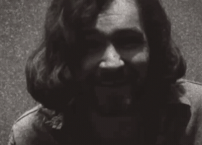 A Black And White Photo Of A Man With Long Hair And A Beard Smiling . GIF